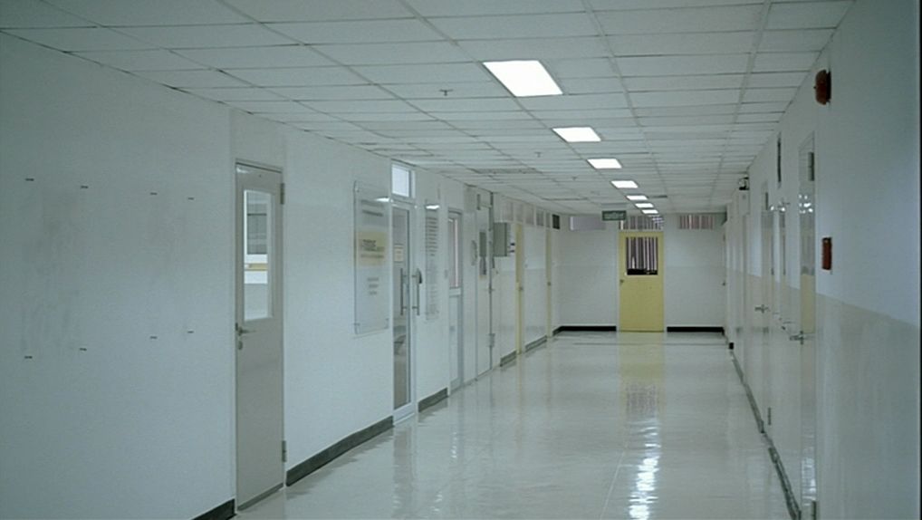 An empty white hospital corridor under fluorescent light
