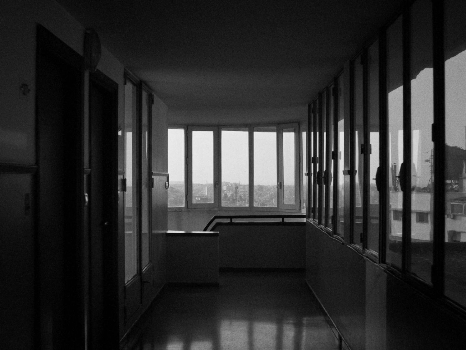 An empty corridor in black and white, windows at the far end