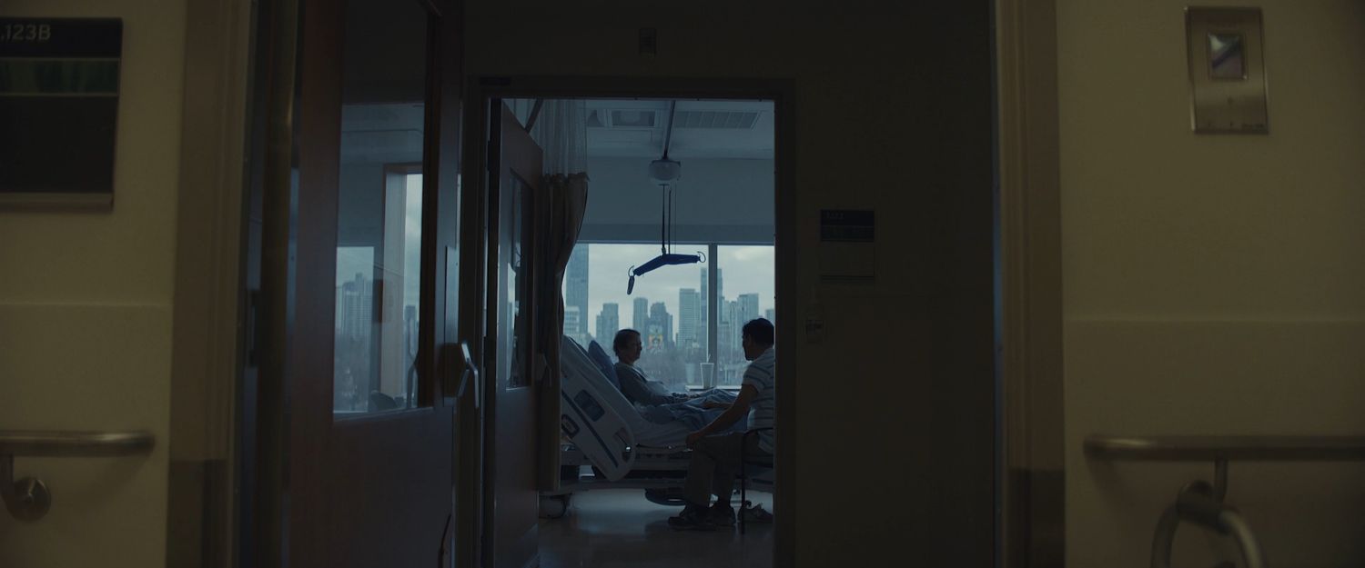 A patient and a visitor seen through a doorway from the hall