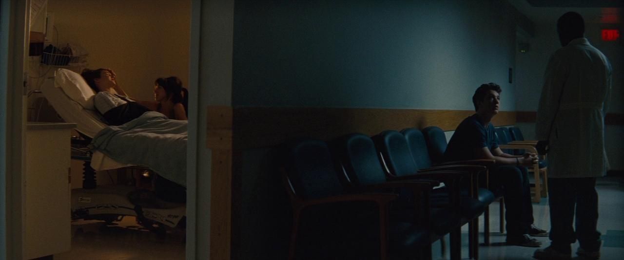 A young man waiting on a row of chairs in a hospital hallway